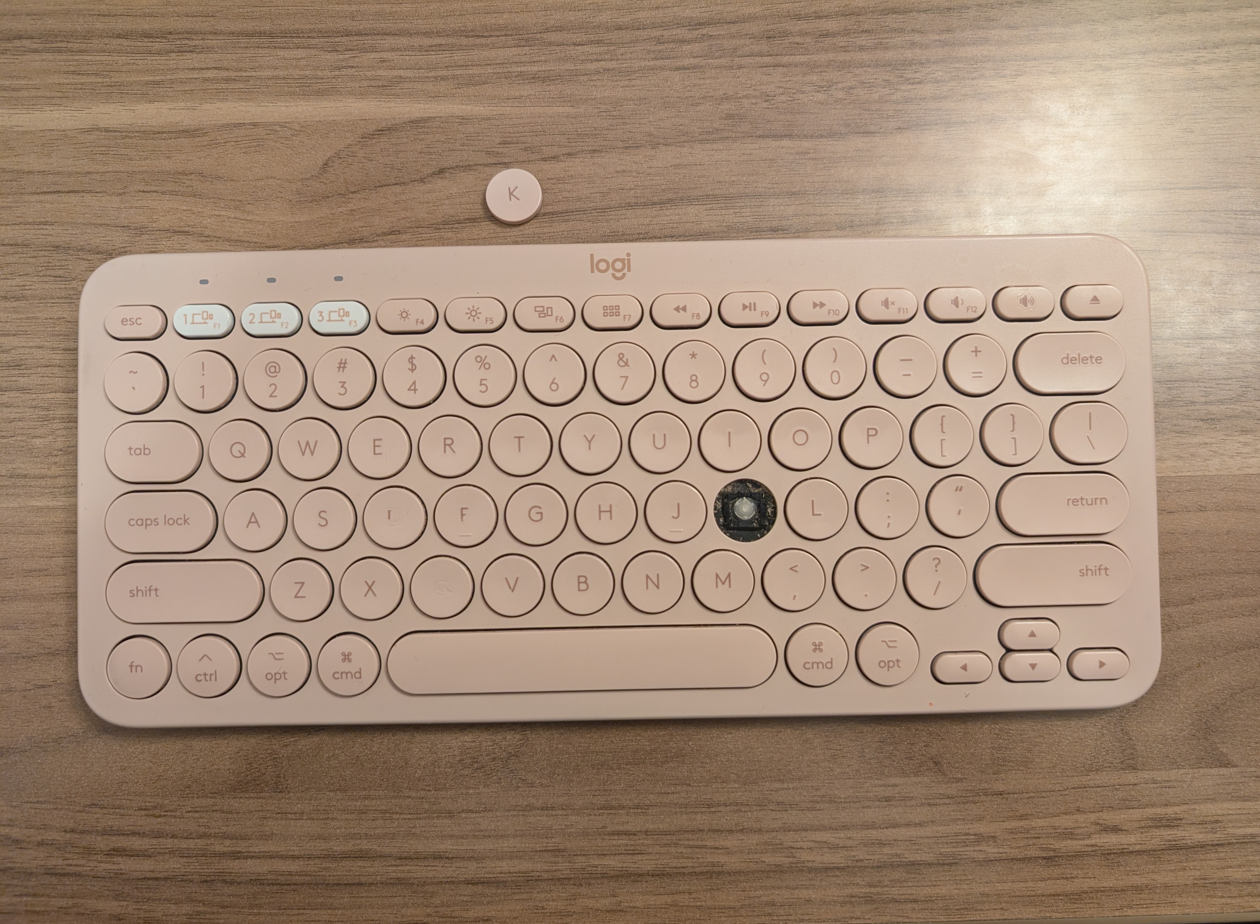 A monochromatic pale pink keyboard with the K key broken off