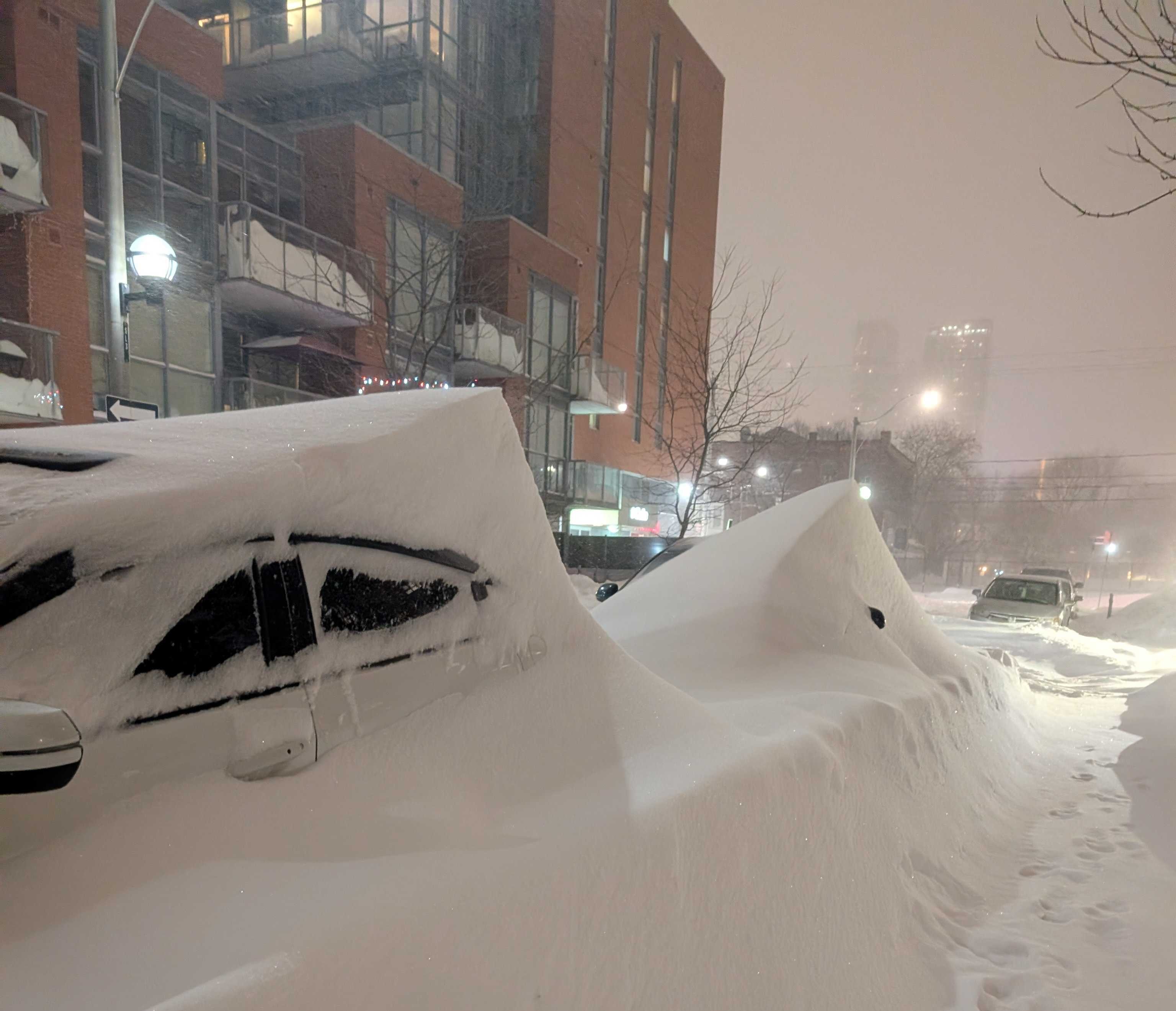 Cars almost buried under piles of snow
